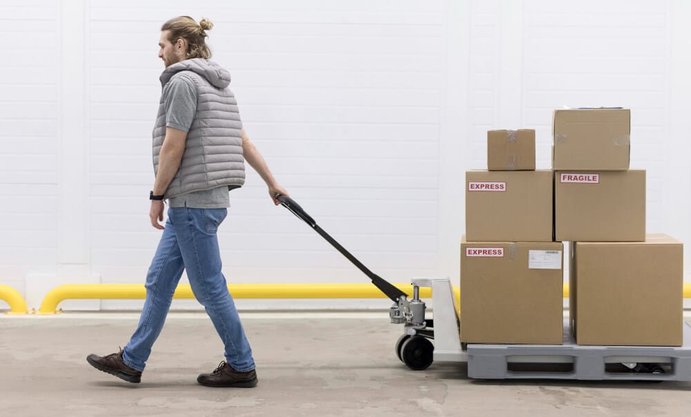 Warehouse worker moving fragile and express-labeled parcels on a pallet jack