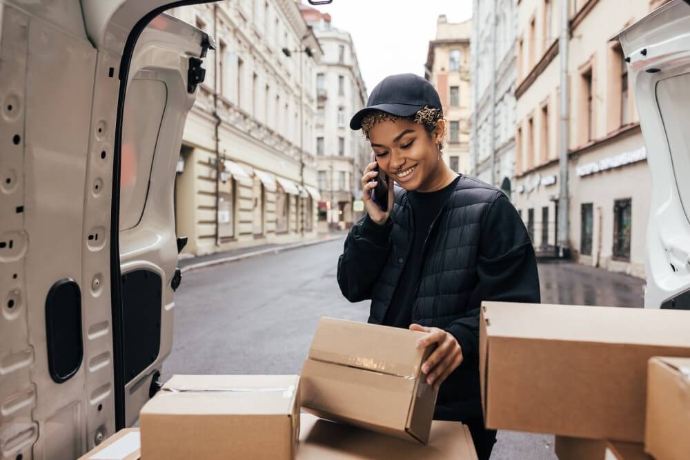 Courier organizing delivery packages in an urban area while coordinating by phone