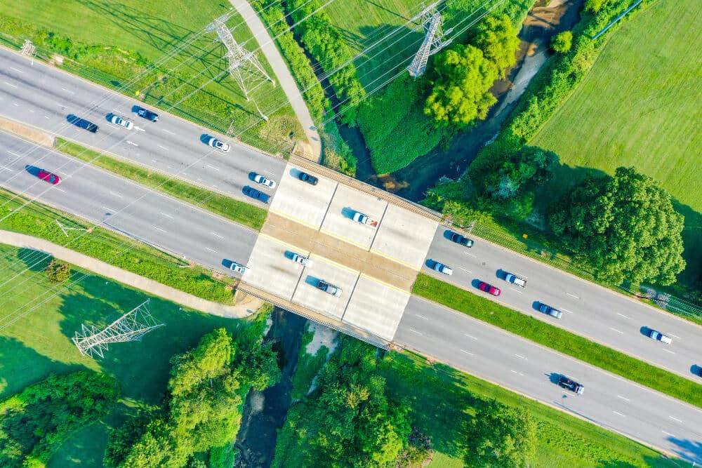 Aerial view of vehicles moving on a multi-lane highway surrounded by greenery.