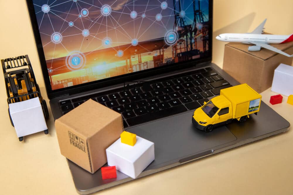 Mini logistics models on a laptop symbolizing digital delivery management.