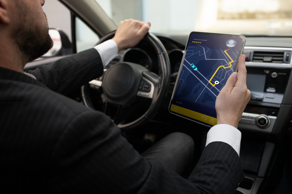 Driver using a tablet with a digital navigation route displayed.