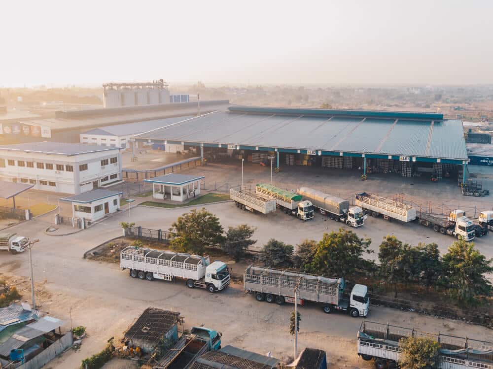 Aerial view of a logistics hub with stacked shipping containers and rail freight lines