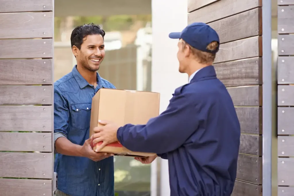 Delivery worker handing a package to a smiling customer at the doorstep.
