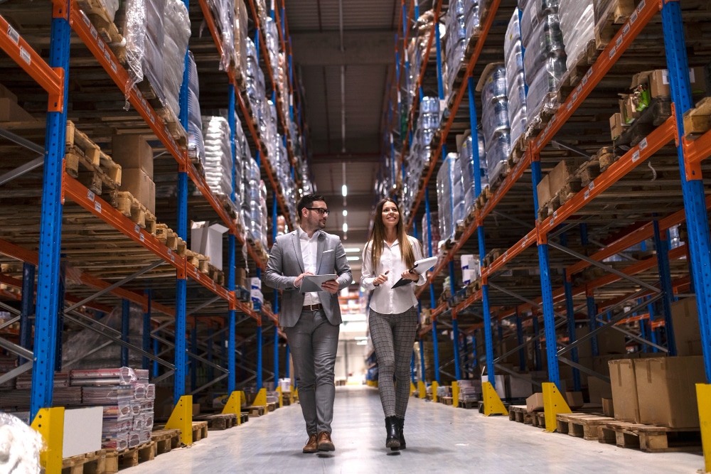 Warehouse managers walk through a large distribution center, inspecting inventory