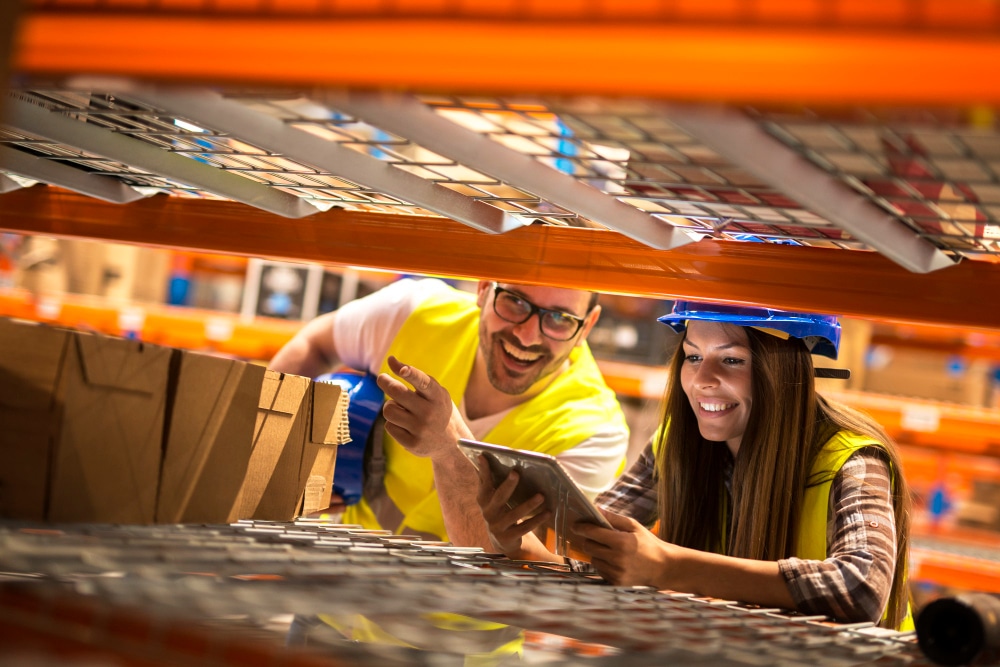 Warehouse workers counting boxes on tall shelves in a large distribution warehouse, illustrating inventory management and logistics operations
