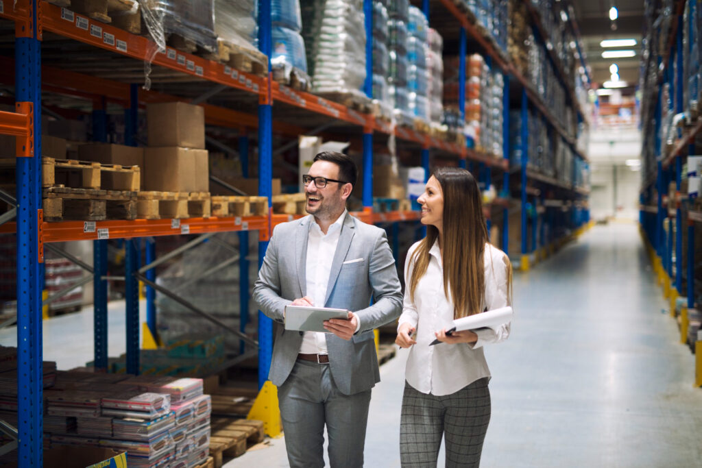 Warehouse workers discussing inventory and logistics planning in a CPG distribution center.